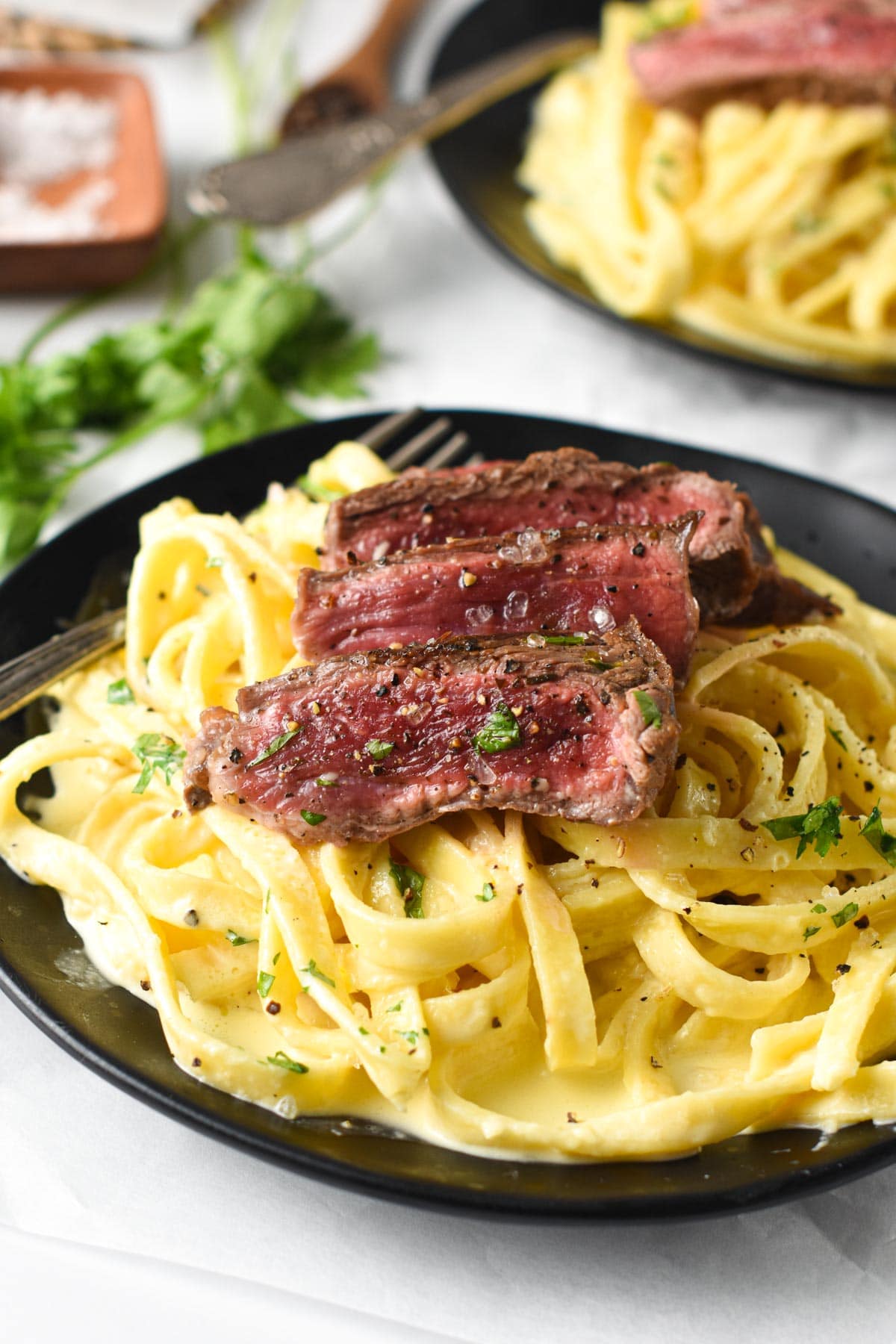 Steak Alfredo slices on top of fettuccine cooked in a creamy alfredo sauce.