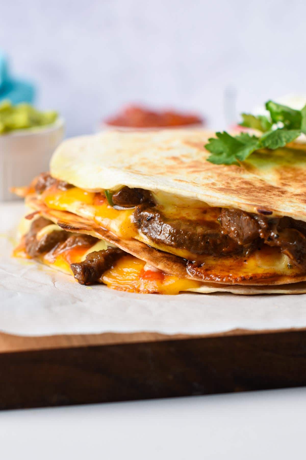 Steak Quesadilla on a chopping board with cilantro on top.