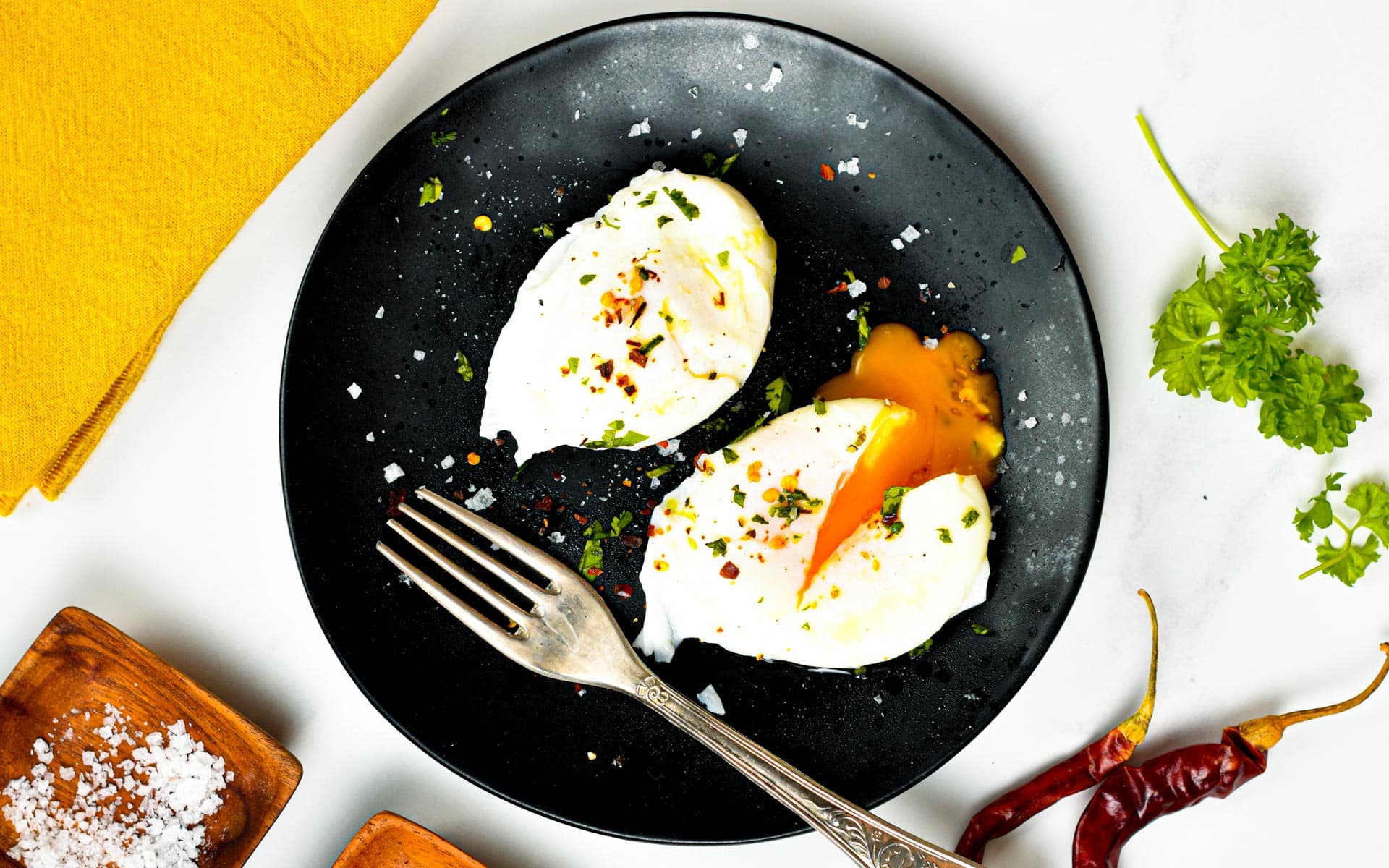 Poached eggs on a black plate with a fork.