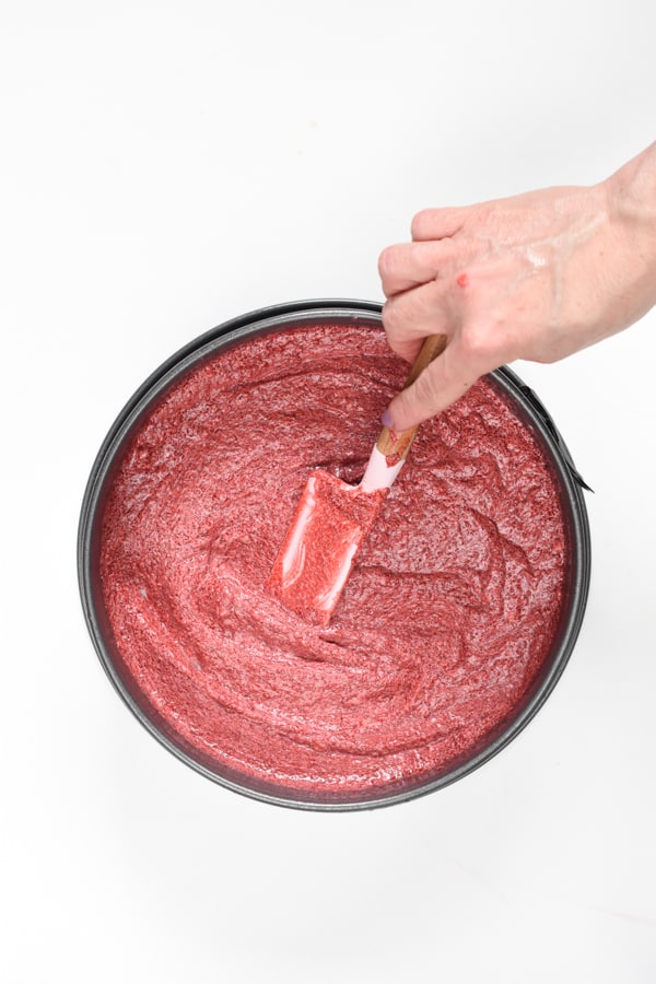 Spreading the keto red velvet cake batter in a springform pan with a silicone spatula.