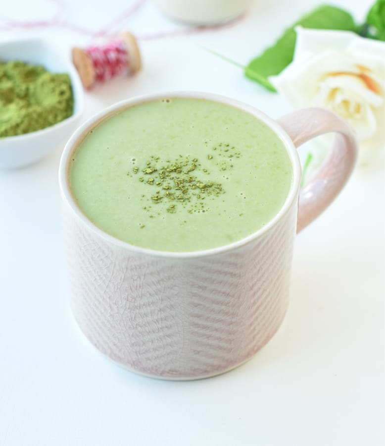 Keto Matcha Latte in a large short mug with matcha powder on top . 